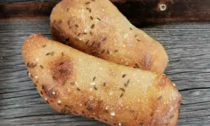Zwei frisch gebackene Seelen mit Kümmel und Salz auf rustikalem Holz.