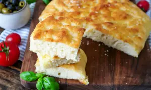 Frisch gebackenes Focaccia-Rezept, aufgeschnitten und gestapelt, mit Tomaten und Oliven daneben.