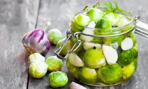 Frischer Rosenkohl und Knoblauch werden für das Rosenkohl einlegen in ein Glas gefüllt.
