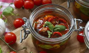Eingeweckte Tomaten in Öl, garniert mit Basilikum. Die Haltbarkeit von Eingewecktem ist oft lang, wenn richtig gelagert.