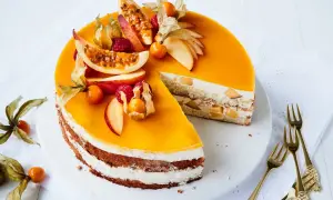 Eine köstliche Maracuja Torte mit frischen Früchten und Sahne. Ein Stück ist bereits angeschnitten, daneben liegen goldene Gabeln.