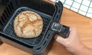 Ein goldbraunes Brot liegt im Korb eines Airfryers. Perfekt für schnelles brot backen im airfryer.