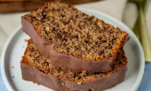 Zwei Scheiben saftiger Schoko Nuss Kuchen mit Schokoladenglasur auf einem Teller.