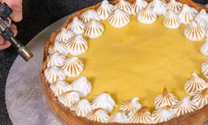 Ein köstlicher Lemon Curd Kuchen mit Baiserhauben wird mit einem Brenner karamellisiert.