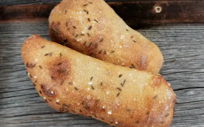 Zwei frisch gebackene Seelen mit Kümmel und Salz auf rustikalem Holz.