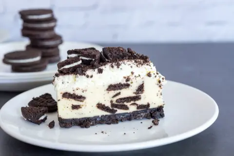 Ein cremiges Stück Oreo Cheesecake mit zerbröselten Keksen und Sahne.