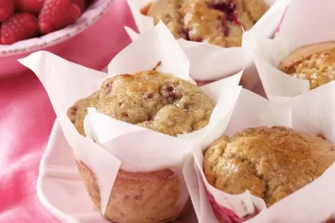 Leckere protein muffins rezept mit Himbeeren, frisch gebacken und auf einem rosa Teller angerichtet.