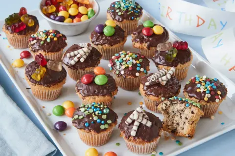 Bunte Muffins mit Schokoglasur und Gummibärchen, perfekt für einen Kindergeburtstag.