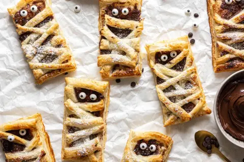 Leckere Mumien-Törtchen mit Schokocreme, ein tolles Rezept für Halloween! Mit Zucker bestäubt und lustigen Augen.