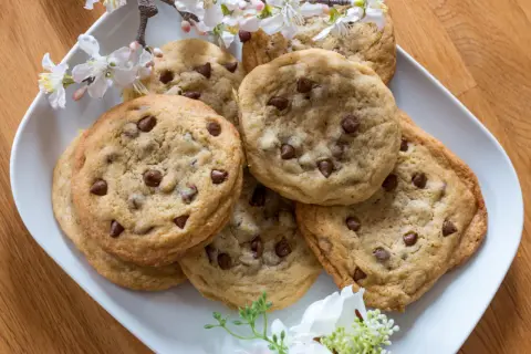 Ein Teller mit frisch gebackenen Schoko Cookies, verziert mit zarten Blüten.