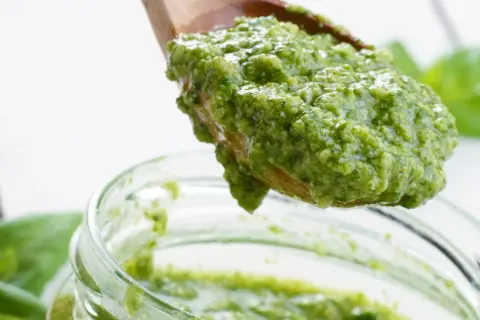 Frisch zubereitetes Basilikum-Pesto auf einem Holzlöffel, bereit für das Einmachen. Ein tolles Rezept für Basilikum-Pesto auf Vorrat.