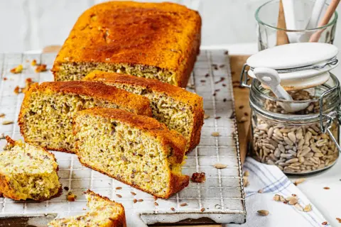 Ein saftiges low carb brot rezept mit Sonnenblumenkernen und Leinsamen, frisch aufgeschnitten auf einem Gitter.