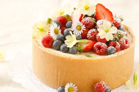 Torte mit frischen Beeren und Blumen dekoriert.