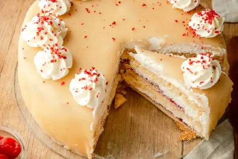 Ein köstliches Marzipantorte Rezept: saftiger Kuchen mit Marzipan, Sahne und Himbeermarmelade, verziert mit Tupfen und roten Streuseln.