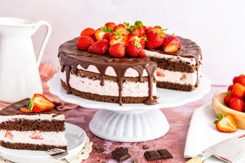 Schokoladenkuchen mit Erdbeercreme, Schokoladenglasur und frischen Erdbeeren, ein Stück angeschnitten.