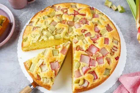 Ein saftiger, schneller Rhabarberkuchen mit vielen roten und grünen Rhabarberstücken, bereit zum Genießen.