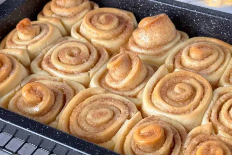 Frisch gebackene, gesunde Zimtschnecken in einer Backform. Sie duften nach Zimt und Zucker und sind bereit zum Genießen.