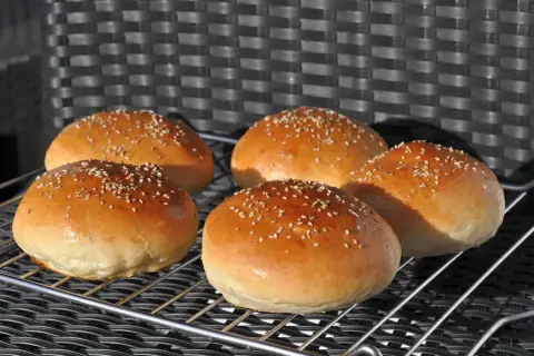 Fünf goldbraune Burger Buns mit Sesam, frisch gebacken nach einem tollen burger buns rezept.