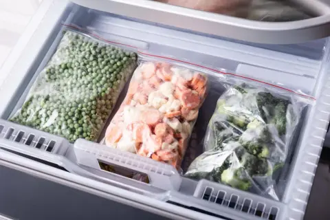 Gefrierbeutel mit Erbsen, Karotten und Brokkoli im Gefrierschrank. So kann man Gemüse einfrieren und länger haltbar machen.