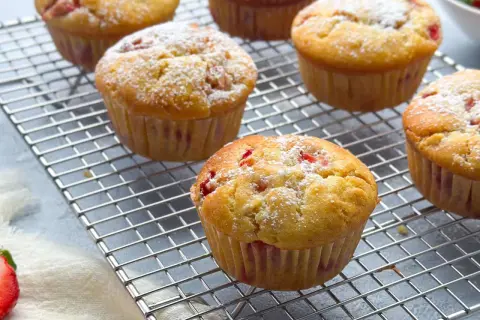 Frisch gebackene erdbeer muffins, mit Puderzucker bestäubt, auf einem Kuchengitter.