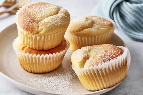 Saftige Muffins mit Quark, bestäubt mit Puderzucker, auf einem Teller arrangiert.