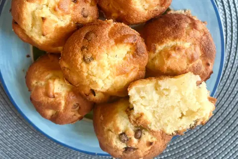 Saftige Apfelmus Muffins mit Schokostückchen auf einem blauen Teller. Einer ist aufgeschnitten und zeigt die lockere Textur.