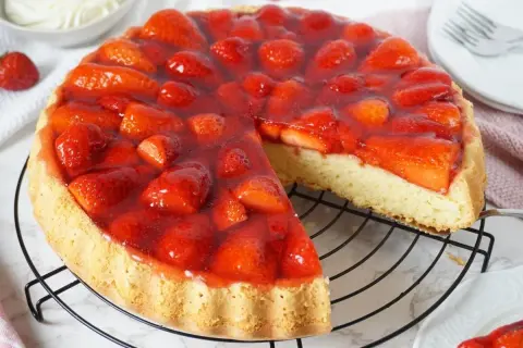 Eine saftige Erdbeer Torte mit frischen Früchten und glänzendem Tortenguss auf einem Gitterrost.