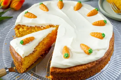 Ein saftiger Karottenkuchen mit cremiger Glasur, verziert mit kleinen Marzipanmöhren. Typische Osterkuchen-Deko.