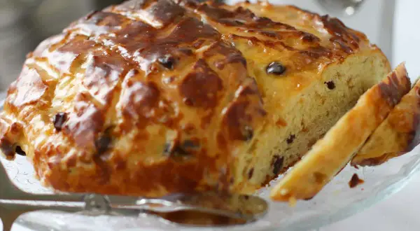 Ein goldbraun gebackenes Osterbrot mit Rosinen, glasiert und angeschnitten, bereit zum Genießen.