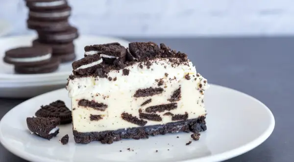 Ein cremiges Stück Oreo Cheesecake mit zerbröselten Keksen und Sahne.