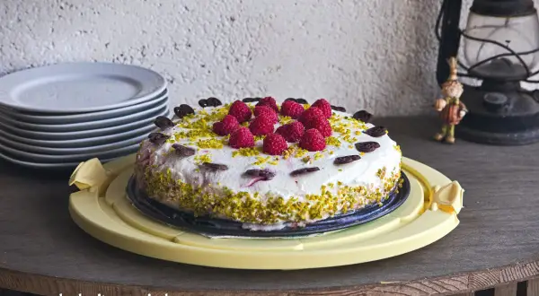 Himbeer Joghurt Torte mit frischen Beeren und Pistazien, verziert mit Schokoladenherzen. Ein Genuss für jeden Anlass.