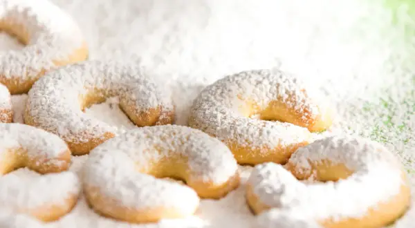 Vanillekipferl, zart und mit Puderzucker bestäubt, liegen auf einer grünen Unterlage. Ein süßer Genuss!