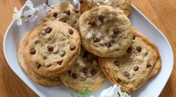 Ein Teller mit frisch gebackenen Schoko Cookies, verziert mit zarten Blüten.