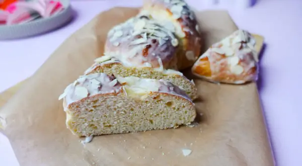Süßer Hefezopf, frisch gebacken und mit Zuckerguss und Mandelsplittern verziert. Ein tolles Rezept für den Kaffeetisch.