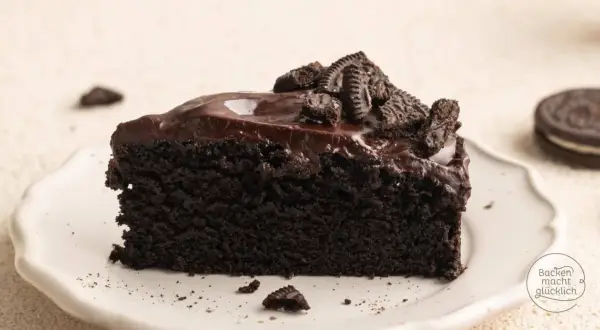 Ein Stück saftiger Oreo Kuchen mit glänzender Schokoladenglasur und zerbröselten Keksen obendrauf.