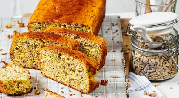 Ein saftiges low carb brot rezept mit Sonnenblumenkernen und Leinsamen, frisch aufgeschnitten auf einem Gitter.