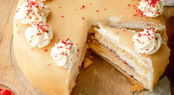 Ein köstliches Marzipantorte Rezept: saftiger Kuchen mit Marzipan, Sahne und Himbeermarmelade, verziert mit Tupfen und roten Streuseln.