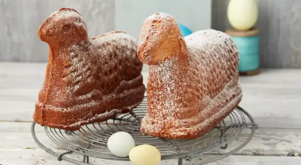 Zwei goldbraune Osterlämmer, mit Puderzucker bestäubt, auf einem Gitter. Ein perfektes Osterlamm Rezept für das Fest.