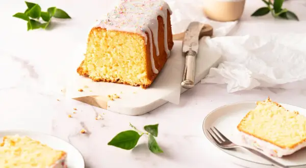 Ein saftiger Zitronenkuchen in Kastenform, mit Zuckerguss und bunten Streuseln verziert, wartet auf seine Genießer.