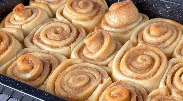 Frisch gebackene, gesunde Zimtschnecken in einer Backform. Sie duften nach Zimt und Zucker und sind bereit zum Genießen.