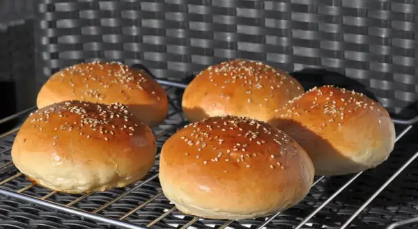 Fünf goldbraune Burger Buns mit Sesam, frisch gebacken nach einem tollen burger buns rezept.