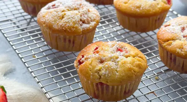 Frisch gebackene erdbeer muffins, mit Puderzucker bestäubt, auf einem Kuchengitter.