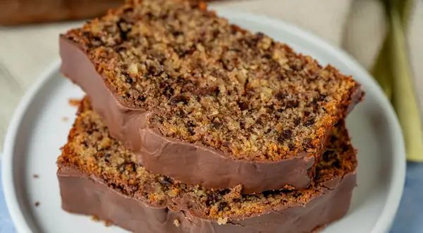 Zwei Scheiben saftiger Schoko Nuss Kuchen mit Schokoladenglasur auf einem Teller.