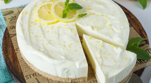 Cremige Philadelphia Torte mit Zitronenscheiben und Minze, ein Stück wurde bereits entnommen.
