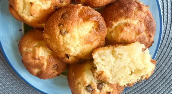 Saftige Apfelmus Muffins mit Schokostückchen auf einem blauen Teller. Einer ist aufgeschnitten und zeigt die lockere Textur.