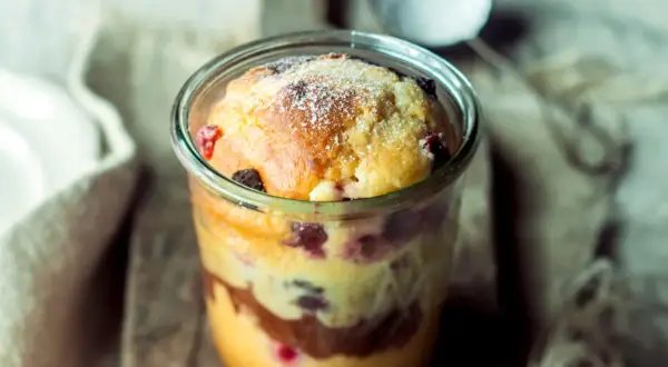 Saftiger Kuchen im Glas mit Beeren und Schokoschichten, bestäubt mit Puderzucker. Ein Genuss zum Löffeln!