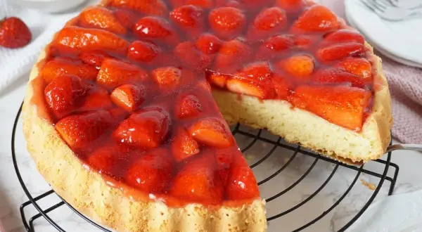 Eine saftige Erdbeer Torte mit frischen Früchten und glänzendem Tortenguss auf einem Gitterrost.