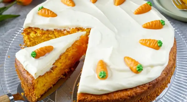 Ein saftiger Karottenkuchen mit cremiger Glasur, verziert mit kleinen Marzipanmöhren. Typische Osterkuchen-Deko.