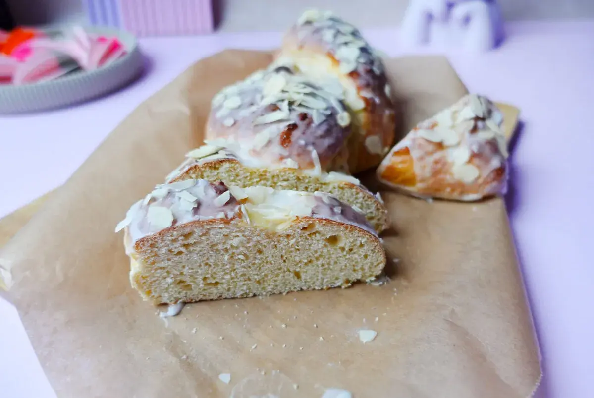 Süßer Hefezopf, frisch gebacken und mit Zuckerguss und Mandelsplittern verziert. Ein tolles Rezept für den Kaffeetisch.