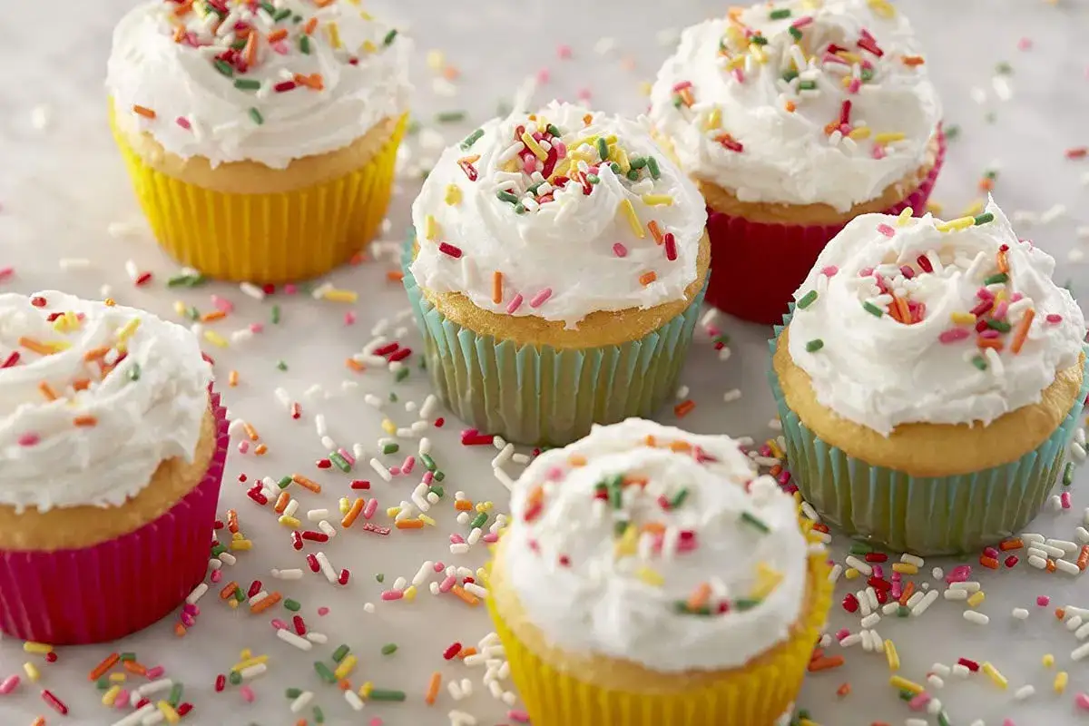 Bunte Mini Muffins mit weißer Glasur und Streuseln, perfekt für ein schnelles Mini Muffins Rezept.